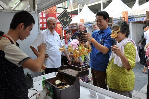 中国侨网Central World 门前地坛庙会曼谷行中，北京民俗艺术展示“吹糖“ 吸引了很多泰国民众驻足。(赵艳蓉 摄）