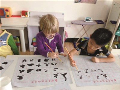 中国侨网斯汀的孩子（左一）学写汉字。（王英 摄）