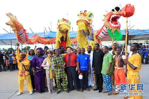 中国侨网在“2015贝宁第六届欢乐春节”广场巡演活动现场,贝宁青年、体育和娱乐部长萨福(前排左四)与龙狮队员等合影。