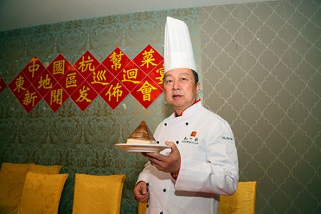中国侨网迷宗菜”创始人胡忠英展示招牌菜“金牌扣肉”。(美国《侨报》/宋?D 摄)