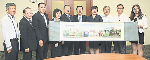 中国侨网刘鑫(右四)将画有湖南中医药大学的一幅画像赠送予郭怡捷(右五)接领。左起为林新和、高宗志、文业景、郭璧妹与李广贤;右起冯玉、庄诒栈与林乐铭。(马来西亚《南洋商报》)