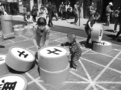 中国侨网华埠游乐区的孩童将巨大象棋当积木玩，充满童趣与创意。(许雅钧 摄)