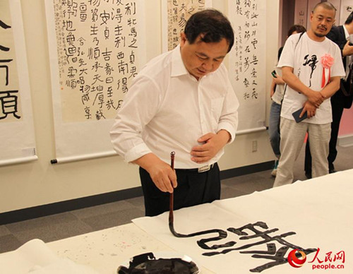 中国侨网曾祥富在展览会现场创作书法作品