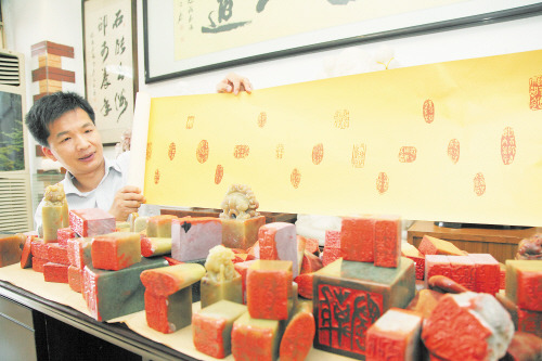 中国侨网在工作室里,林旭平正向记者展示自己的系列篆刻作品《离骚》。(陈飞 摄)