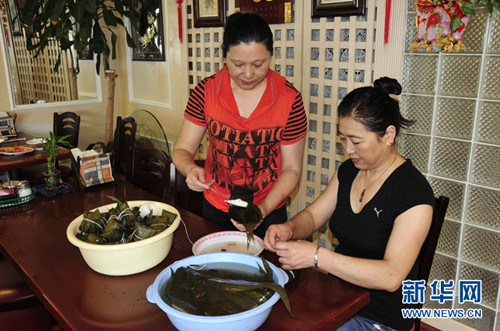 中国侨网中央饭店两位女工正在包北方口味的大枣米粽。（张永兴 摄）