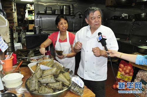 中国侨网锦江酒家老板正在给记者介绍该店上海嘉兴肉粽子的销售情况。（张永兴 摄）