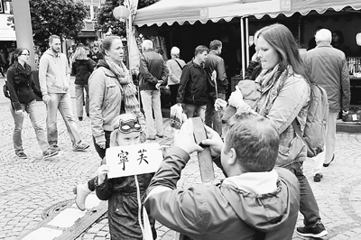 一名德国女孩举着用中国书法写的自己的名字留影纪念。（冯雪珺