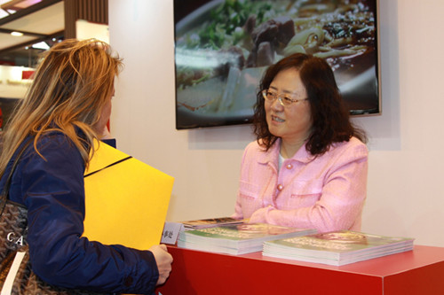 国家旅游局驻巴黎办公室主任薛桂凤（右）正在中国展台前与咨询的参观者进行交流。（法国《欧洲时报》/张新