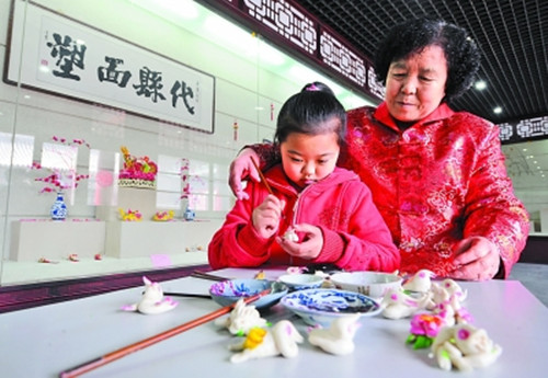 山西非物质文化遗产代县面塑传人张桂英正在传授孙女面塑手艺(资料图)
