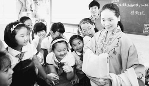 5月31日,浙江省新昌县调腔剧团演员曹晓云(右一)为南岩小学学生讲解新昌调腔的戏服特点。(新华社记者刘勇贞