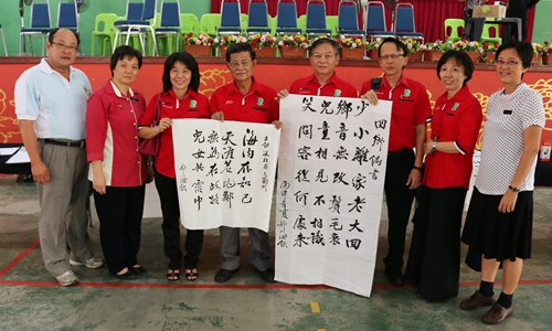 嘉宾在会上展示郑海钦（左四）所挥毫的2副字帖。（马来西亚《星洲日报》）