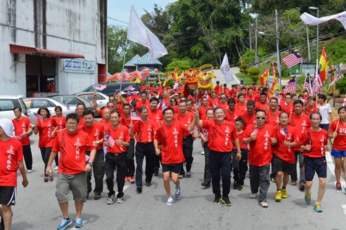 郑来天（右四）和理事郑元鸿（左五）一起护送火炬，大队绕街场跑向终点天福宫。（马来西亚《星洲日报》）