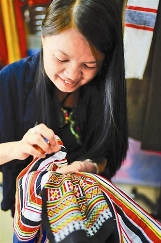 李素芳在做瑶族服装。她希望更多城市人穿上她设计的衣服。（蔡丽）