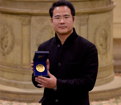 2013年12月5日，在法国巴黎，董强在法兰西学院展示他获得的“法语国家联盟金奖”奖牌。（新华社记者