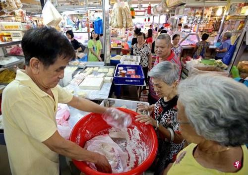中国侨网售卖糯米粉泥已有50多年摊贩陈长福(左)说：“购买糯米粉泥回家自己动手搓汤圆的顾客，大部分是60岁及以上的老一辈人。”(新加坡《联合早报》/叶振忠 摄)