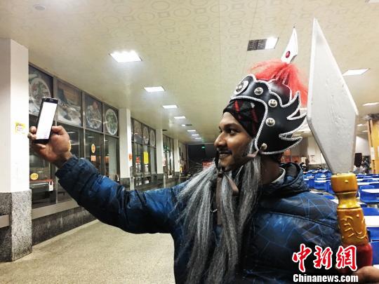 中国侨网装扮成中国古代将军的留学生伊姆一边与记者交流一边用手机自拍。(杨云 摄)