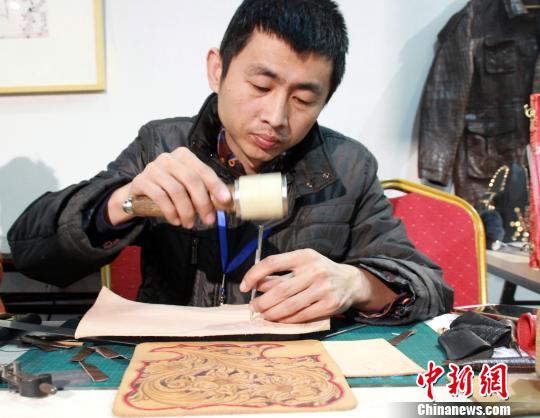 中国侨网谭士伟在现场进行皮雕创作。(于俊亮　摄)