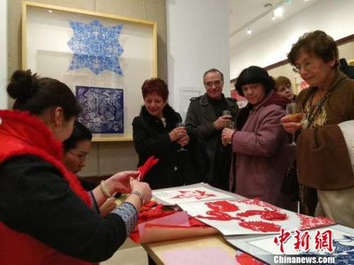 中国侨网“花的絮语-中国剪纸艺术精品展”在马耳他首都瓦莱塔展出。当地民众好奇地观看艺人创作剪纸作品。(王大卫 摄)
