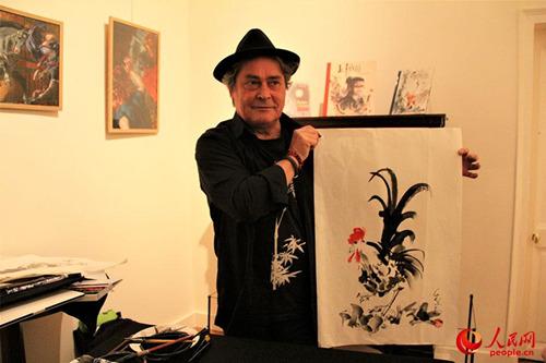 中国侨网法国画家皮尔康展示即兴创作的鸡年主题水墨画。(李永群 摄)