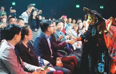 中国侨网当地时间2月5日,“亲情中华”艺术团在葡萄牙里斯本演出,来自四川成都市非物质文化遗产保护中心的演员夏欢在表演川剧变脸时与观众互动。(本报记者 严瑜 摄)
