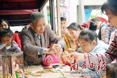 中国侨网茶山公仔传承人林暖钦正在教孩子上色。