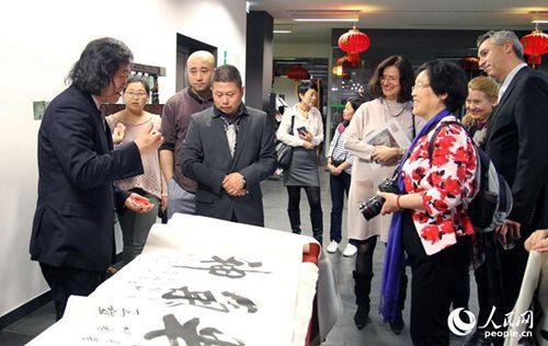 中国侨网北京风情油画家王继民(左1)现场表演书法。人民网记者管克江摄
