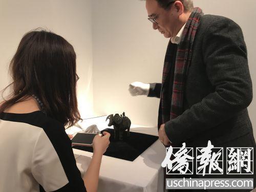 中国侨网一位私人收藏家正在与展馆人员探讨青铜羊觥。(美国《侨报》/李莎菲 摄)