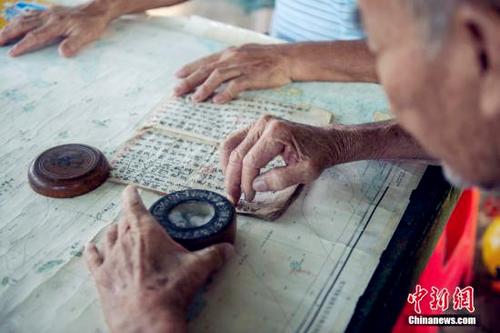 中国侨网资料图:《更路簿》是海南渔民在开发和经营西、南、中沙群岛的过程中,用海南方言字写成,利用文字和地图的方式描绘出的航海手册。其最早出现在元代,盛行于明末、清代和民国时期,记录了南海海域的100多处地名和重要的海洋资讯。时光流逝,彼时的老船长们正逐渐退出历史,只有《更路簿》记录下他们的南海传奇。 中新社记者 骆云飞 摄