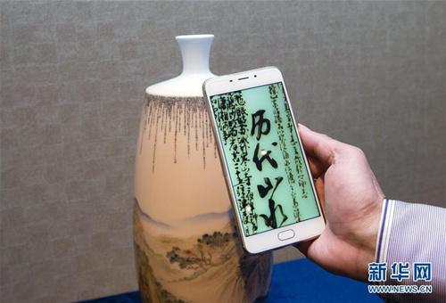 中国侨网5月14日，在瑞士日内瓦举行的陶瓷微书作品展上，一名参观者用手机拍摄一件陶瓷微书展品。（新华社记者 徐金泉 摄）