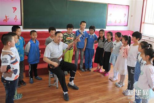中国侨网国家级非物质文化遗产陕北说书市级传承人赵华英在安塞区第四小学教授小学生们演出技艺。(新华社记者 陈昌奇 摄)