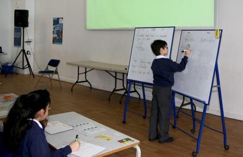 中国侨网资料图片：“九九乘法表”走进英国小学课堂。在英国伦敦东北部埃塞克斯郡的哈里斯小学，一名三年级(相当于国内二年级)的小学生在白板上用竖式计算。 新华社记者韩岩摄