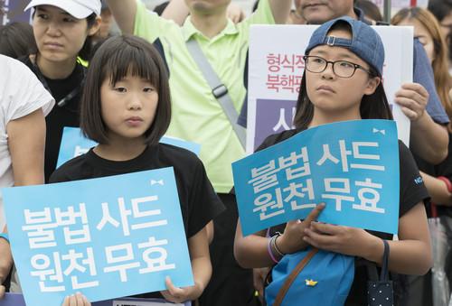 中国侨网资料图片:7月31日,在韩国首尔国防部门前,韩国民众高举反对部署“萨德”系统的标语参加抗议集会。新华社发