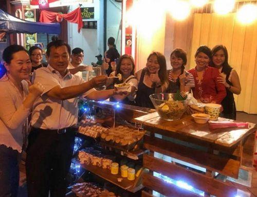 中国侨网马华登州联委会主席杜振耀(左二)光顾华人黄艳莉(右五)和好友们经营的摊口，大赞她们的食物可口。(马来西亚《星洲日报》)