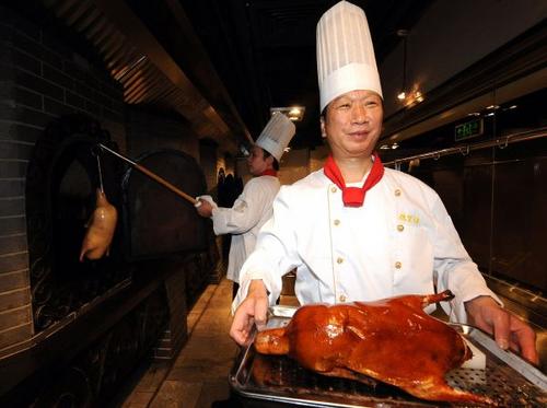 中国侨网资料图:2010年6月6日,焖炉烤鸭技艺第20代传承人白永明(前)烤制出第一只创新“蔬香酥”烤鸭。 新华社记者张旭摄