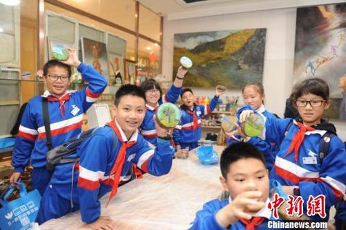 中国侨网图为学生们展示画好的木墩画。