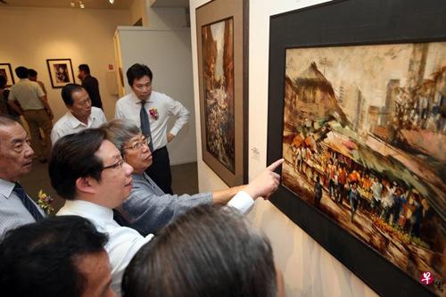 中国侨网翁锡礼（前排左三）介绍他的油画《办年货（牛车水）》。（新加坡《联合早报》/邝启聪 摄）
