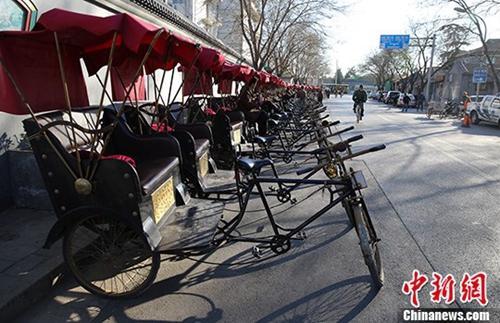 中国侨网资料图：北京什刹海附近胡同里的“人力三轮车”停靠在路边，排成一排。中新社发 熊然 摄