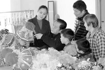 中国侨网11月25日,章思林(左二)在“秧歌灯工作室”里修剪制作彩灯。