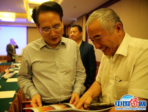 中国侨网作者（右一）在阿拉木图向国务院侨办副主任谭天星展示纪录东干文化的画册。文龙杰 摄