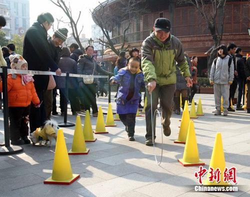 中国侨网资料图：龙年正月初三，在武汉新天地龙年新春庙会上大人小孩一起玩“那些年我们一起玩的游戏”，打弹珠、踢毽子、滚铁圈等。中新社发 张畅 摄