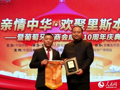 中国侨网“亲情中华”艺术团团长刘奇（右）与葡萄牙华商会会长黄永杰互赠礼品。