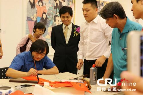 中国侨网青年书法家李剑锋(左一)现场为观展两国嘉宾和民众挥毫泼墨。 摄影:李晓萍
