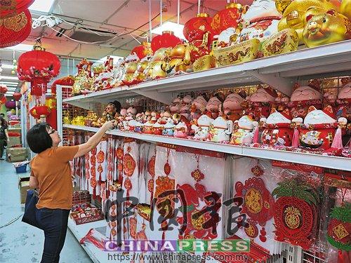 中国侨网商场货架上摆满狗年饰品，民众仔细挑选。（马来西亚《中国报》）