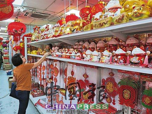 中国侨网商场货架上摆满狗年饰品,民众仔细挑选。(马来西亚《中国报》)