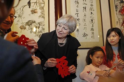 中国侨网资料图:2018年2月2日,特蕾莎·梅在上海参观豫园,同孩子们一起剪纸。(图片来源:中新社)