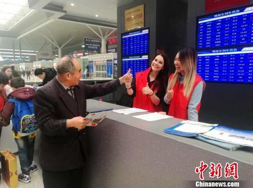中国侨网郑州东站候车大厅内一位老人向两名外国留学生志愿者伸出大拇指点赞。　刘鹏　摄