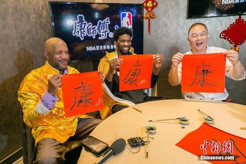 中国侨网本周末，2018年美国男子职业篮球联赛（NBA）全明星赛即将亮相洛杉矶斯台普斯体育馆。在NBA全明星赛前夕，当地时间2月15日下午，效力于费城76人队的NBA当红球星乔尔·恩比德（中）与中国篮球评论员、前国家篮球队运动员张卫平（右一）以及NBA传奇球星罗恩·哈珀（左一），在洛杉矶市中心共同度过洋溢着浓郁中国味道的大年三十。图为恩比德和哈珀展示自己写的中国毛笔字。中新社记者 张朔 摄