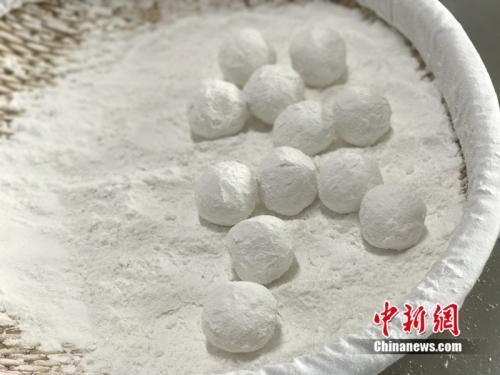 中国侨网做元宵时,首先要将馅料做好,沾上水,再投进盛满糯米粉的笸箩内摇。中新网 吴涛 摄