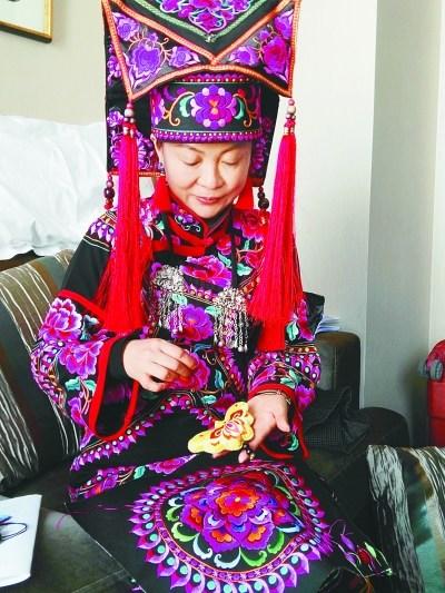 中国侨网罗珺在展示彝族刺绣工艺品。本报记者 张勇摄/光明图片