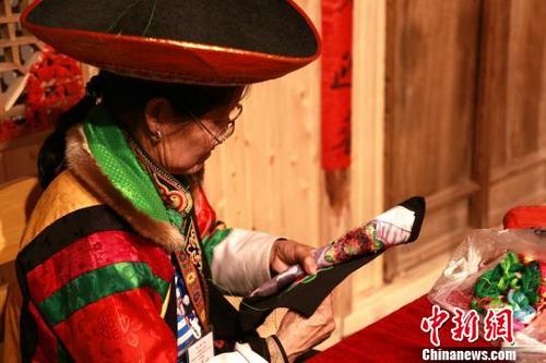 中国侨网 3月29日,青海省美术馆正在展出“中国非物质文化遗产传承人群研修研习培训计划”青海地区的丰硕成果,图为土族阿婆席金花正在绣着一朵太阳花。 马铭言 摄